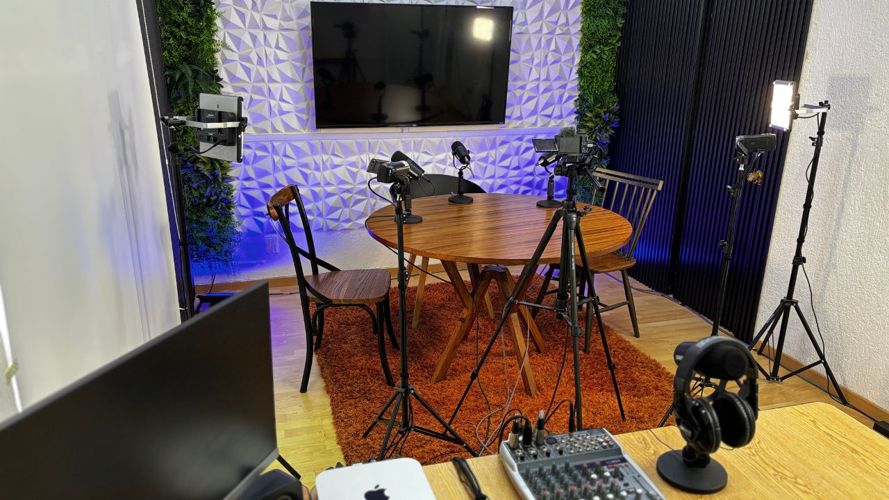 Estudio de podcast con mesa redonda, micrófonos, cámaras e iluminación